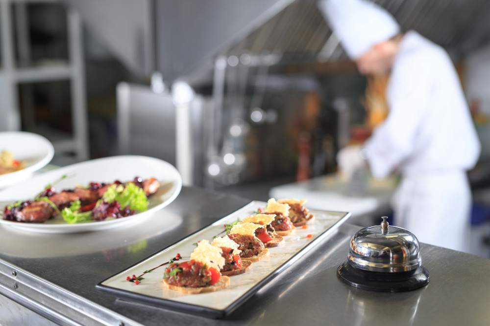 Aperitive gourmet pe tejghea, bucătar în fundal