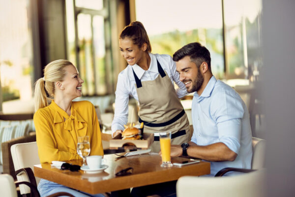 Chelneriță servește burger unui cuplu la restaurant
