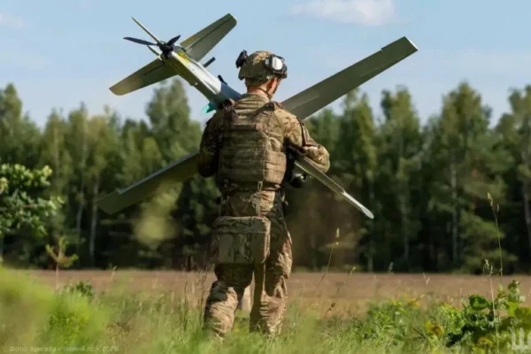 Soldat transportă dronă militară pe câmp