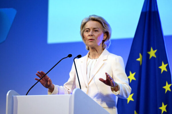 Femeie vorbind la pupitru, steagul Uniunii Europene.
