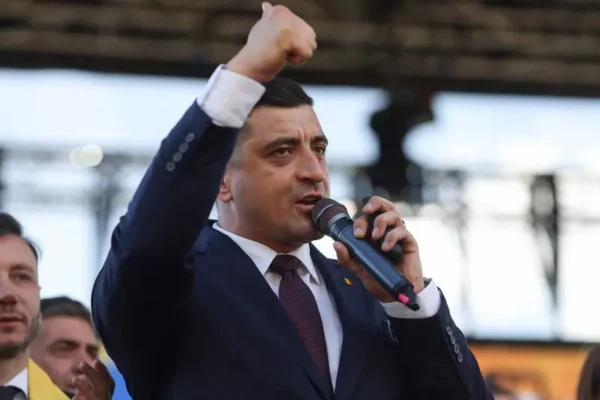 Bărbat în costum vorbește la microfon, ridică pumnul